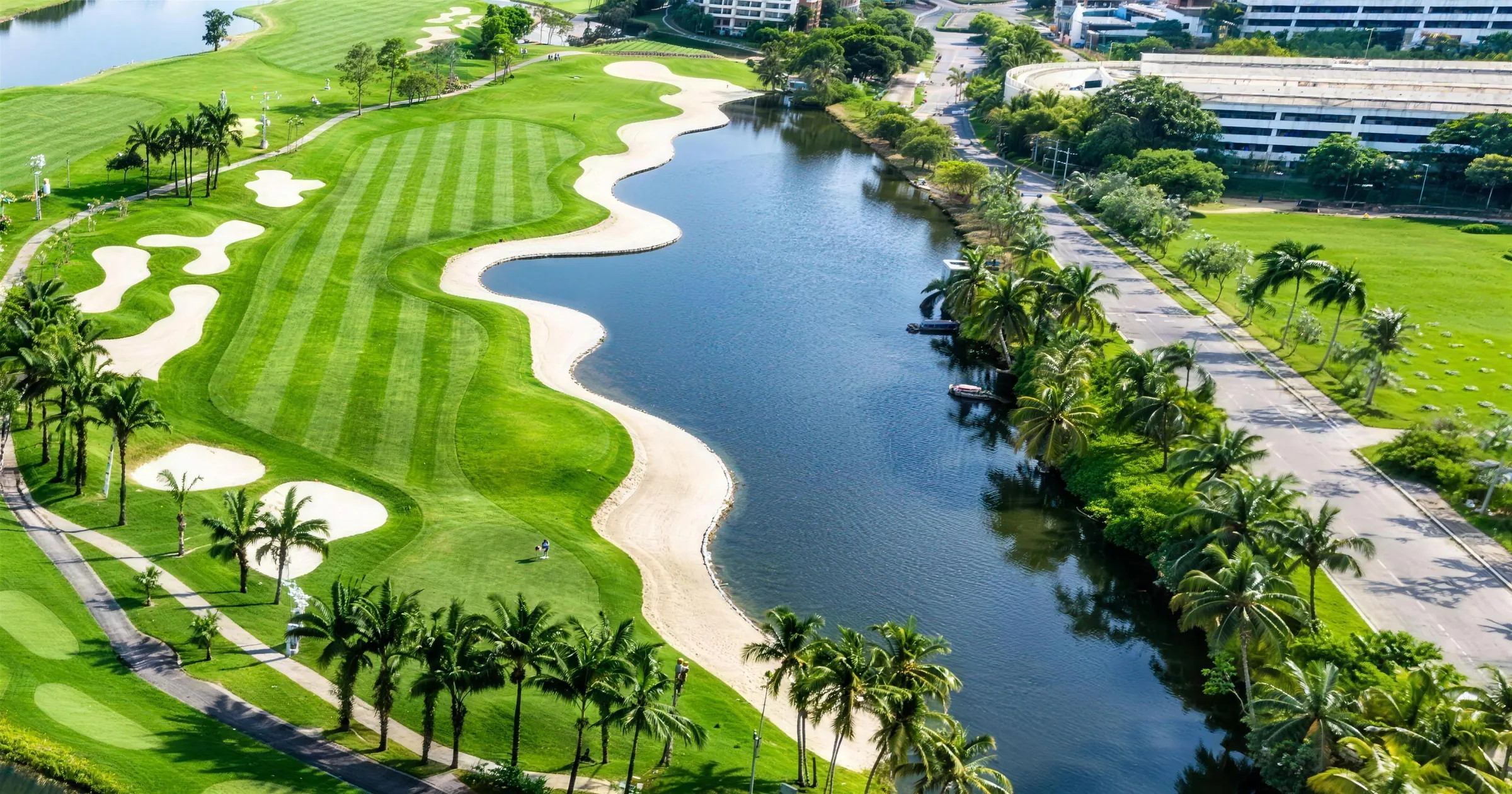 A fairway curving along the lake, lined with white sand